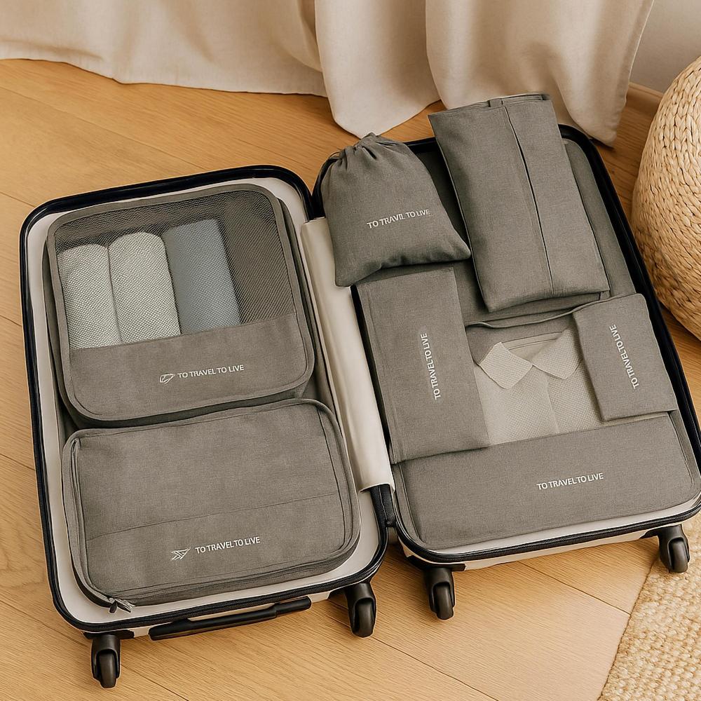 Set of gray packing cubes with 'TO TRAVEL TO LIVE' branding on a suitcase.