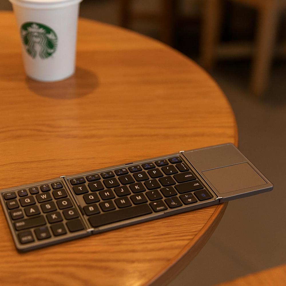 Foldable keyboard on a wooden table with a Starbucks cup in the background