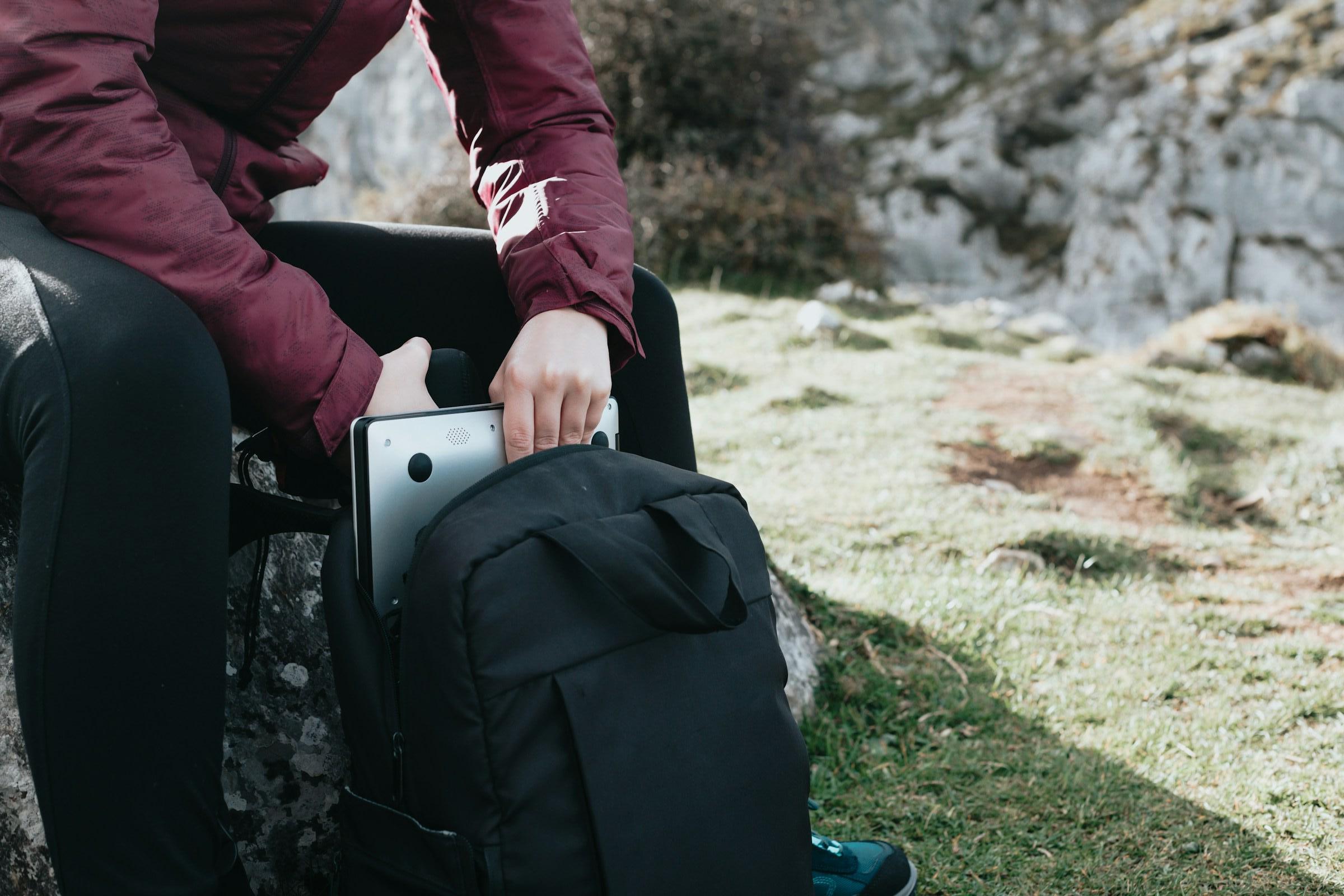 Person sitting outdoors with a backpack and tablet